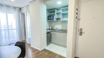 Cocina compacta con microondas, armarios y cafetera.