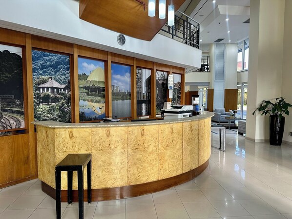 Zona de recepción con un mostrador curvo de madera, un reloj y amplias ventanas con vistas panorámicas.