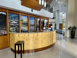 A reception area with a curved wooden counter, a clock, and large windows with scenic views.