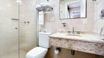 Baño con inodoro, lavabo, espejo y ducha.