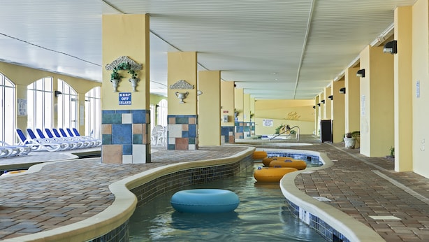 An indoor swimming pool with a brick border, lounge chairs, and a sign that reads "KEEP OFF ISLAND".