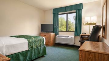 A hotel room with a bed, a desk, a chair, a television, and a window with curtains.