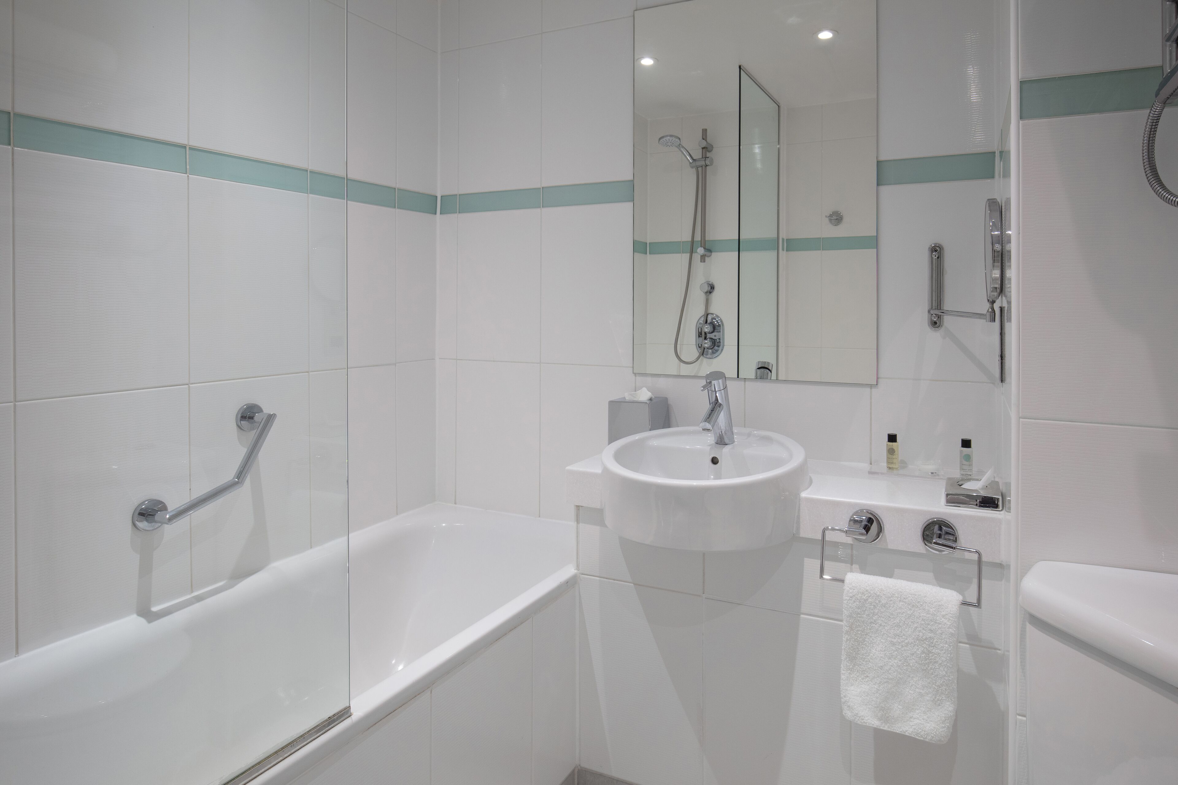 A modern bathroom with a bathtub, a sink, and a mirror.