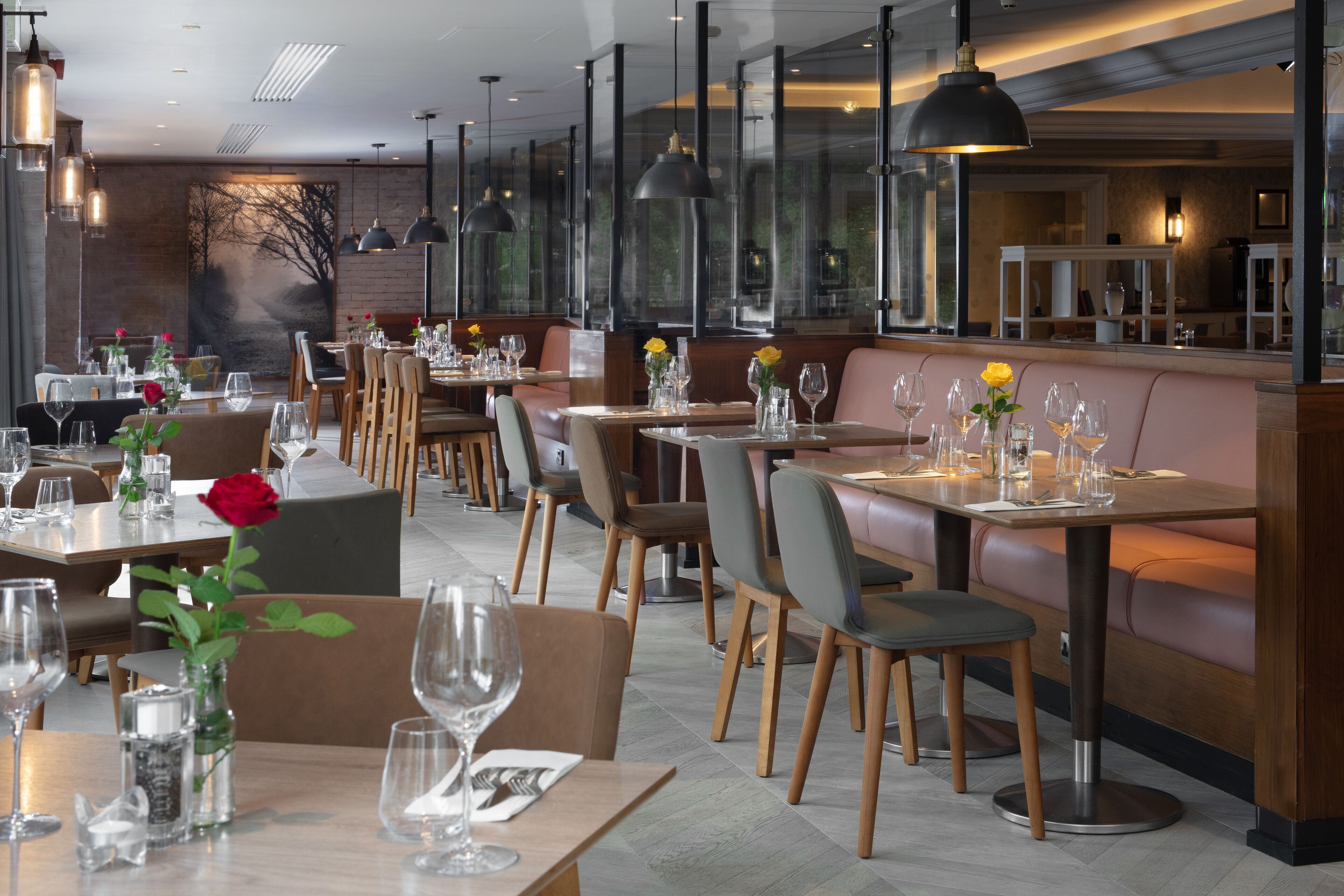 Un restaurante con varias mesas y cabinas, cada una adornada con copas de vino y flores.