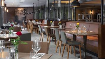 Un restaurante con varias mesas y cabinas, cada una adornada con copas de vino y flores.