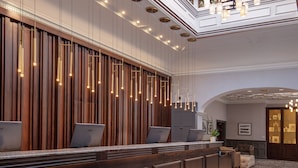 A reception area with a wooden reception desk, multiple computer monitors, and a chandelier. - Chesford Grange Hotel (Kenilworth)