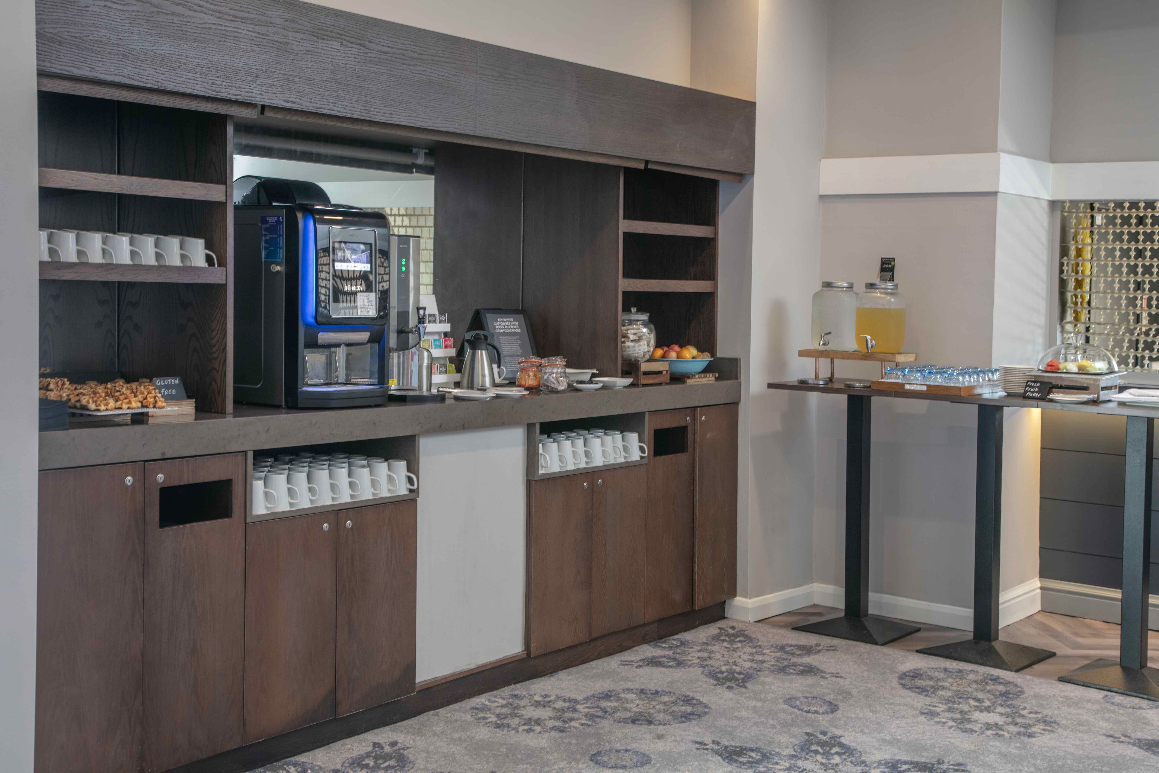 A modern kitchen area with a coffee machine, a coffee station, and a fruit bowl.