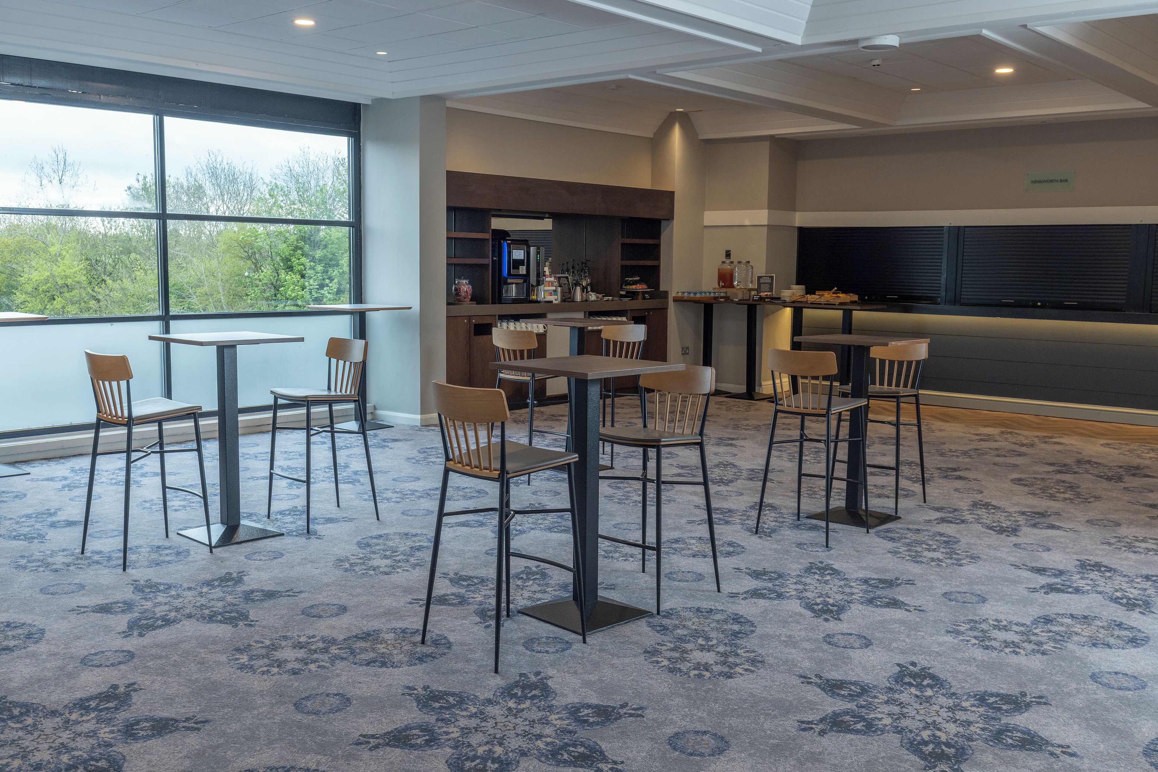 A modern hotel lobby with a bar area, seating arrangements, and large windows offering a view of the outdoors.