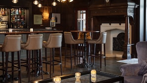A bar area with stools, a coffee table with candles, and a fireplace. - Chesford Grange Hotel (Kenilworth)