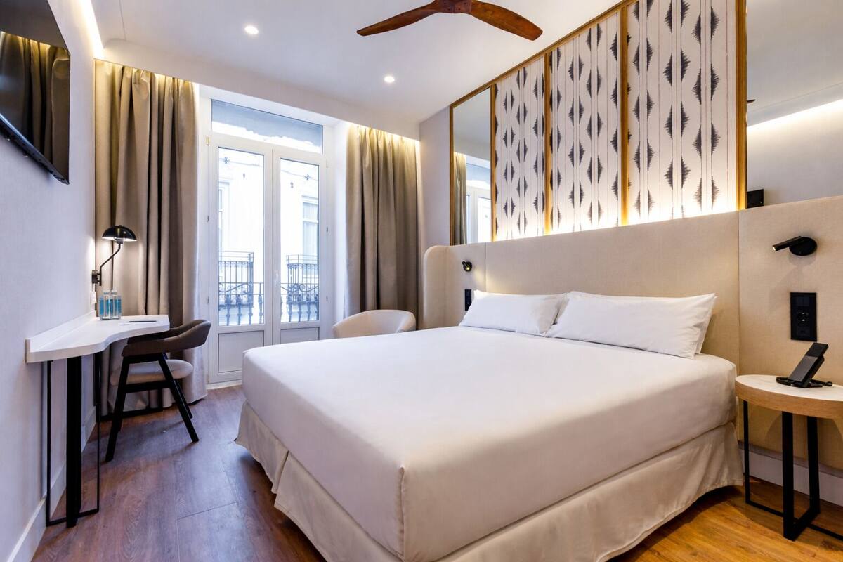 A hotel room with a large bed, a desk, and a chair.