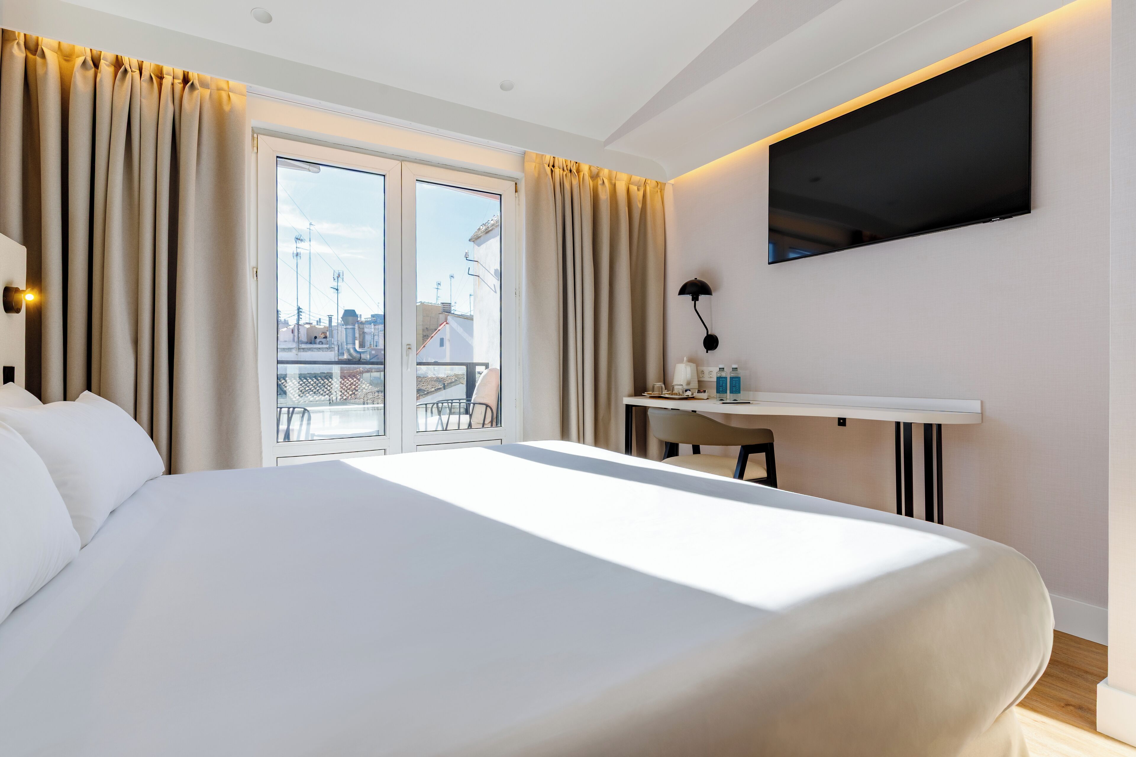 Hotelkamer met een groot bed, een bureau, een flatscreen televisie en een balkon met uitzicht over de stad.