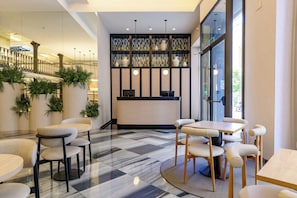 A modern interior with a reception desk, seating area, and decorative shelves. - Petit Palace Plaza de la Reina Hotel (Valencia)