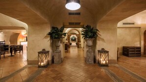 A spacious lobby with a high ceiling, a central light fixture, and two large potted plants. - San Biagio Relais (Orbetello)