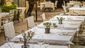 An outdoor dining area with tables set for two, umbrellas, and hanging lamps. - San Biagio Relais (Orbetello)