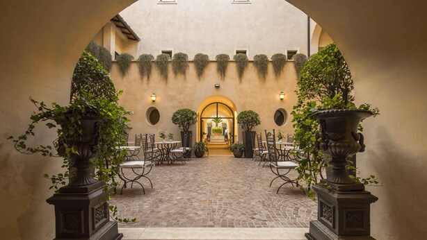 An indoor courtyard with a cobblestone floor, a central archway, and seating areas with tables and chairs. - San Biagio Relais (Orbetello)