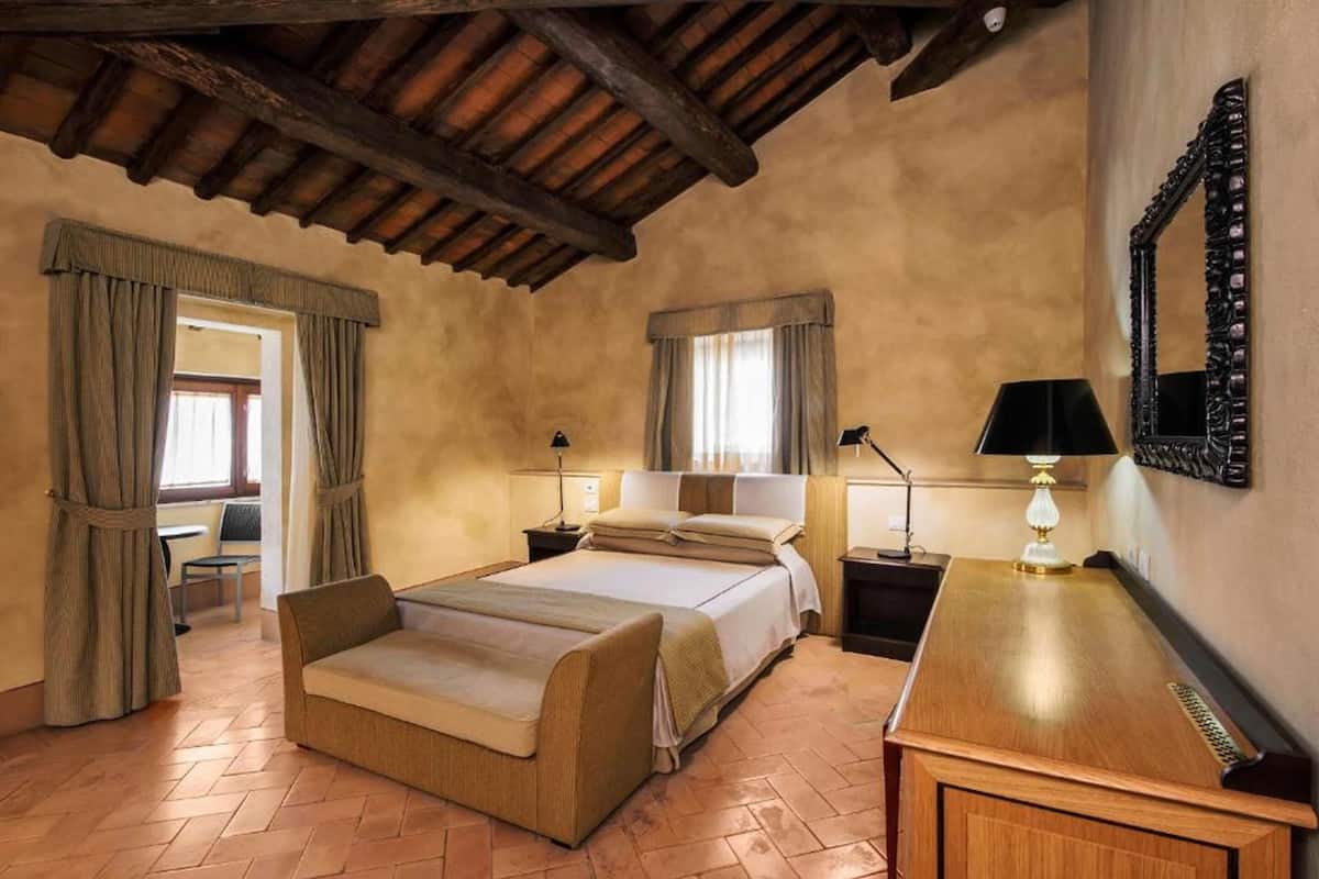 Un dormitorio con cama, mesitas de noche, un escritorio y un espejo.
