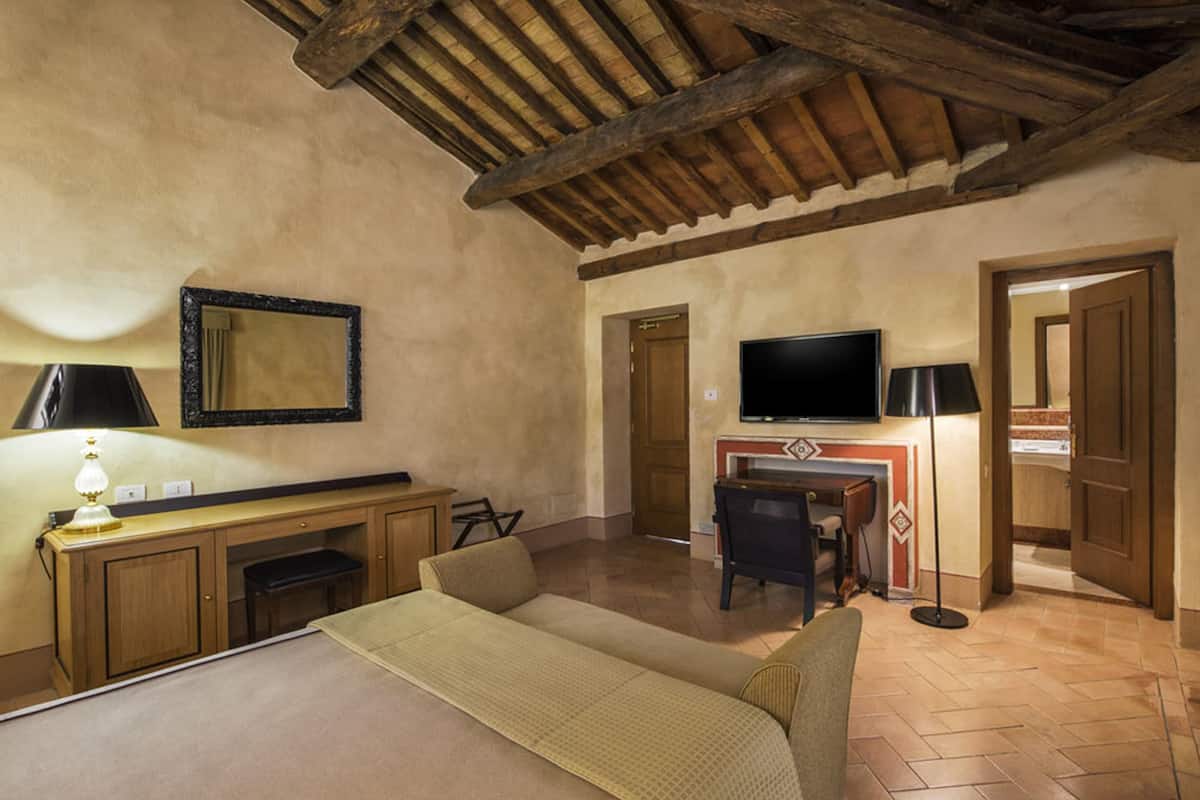 Un dormitorio con cama, escritorio, silla, televisor y lámpara.