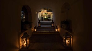A dimly lit hallway with lanterns, leading to a staircase and a small garden area. - San Biagio Relais (Orbetello)