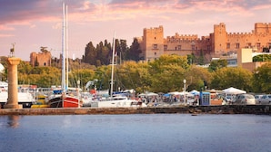 A marina with boats, a castle, and a statue. - Mercure Rhodes Alexia Hotel & Spa (Rhodes)