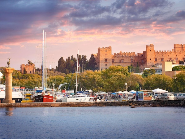 A marina with boats, a castle, and a statue. - Mercure Rhodes Alexia Hotel & Spa (Rhodes)
