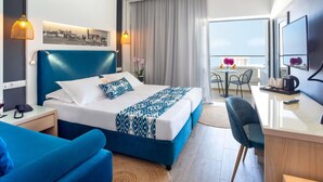 A hotel room with a bed, a desk, a chair, a phone, a TV, and a balcony with a table and chairs. - Mercure Rhodes Alexia Hotel & Spa (Rhodes)