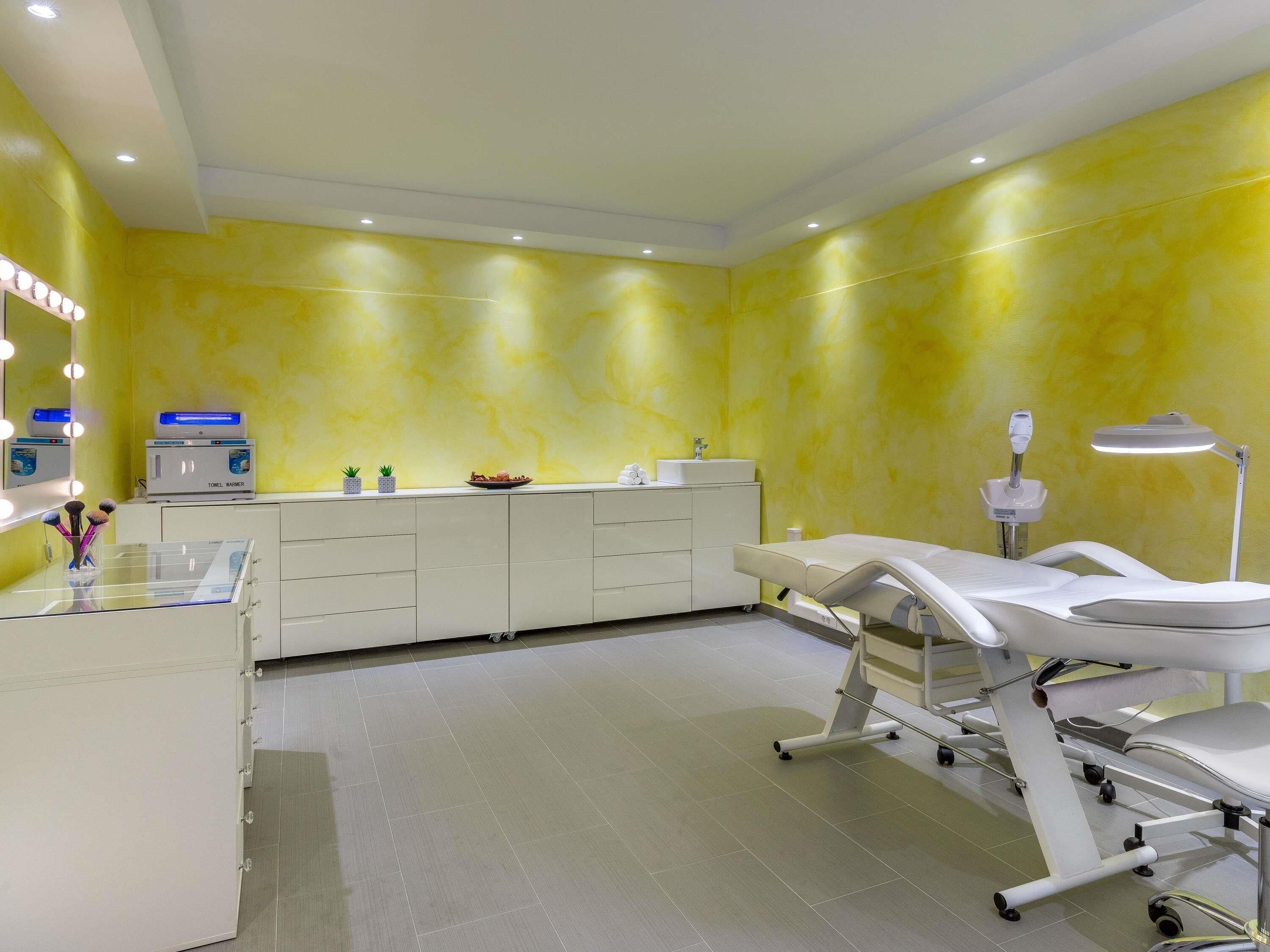 A clinical examination room with a bed, examination table, and medical equipment.