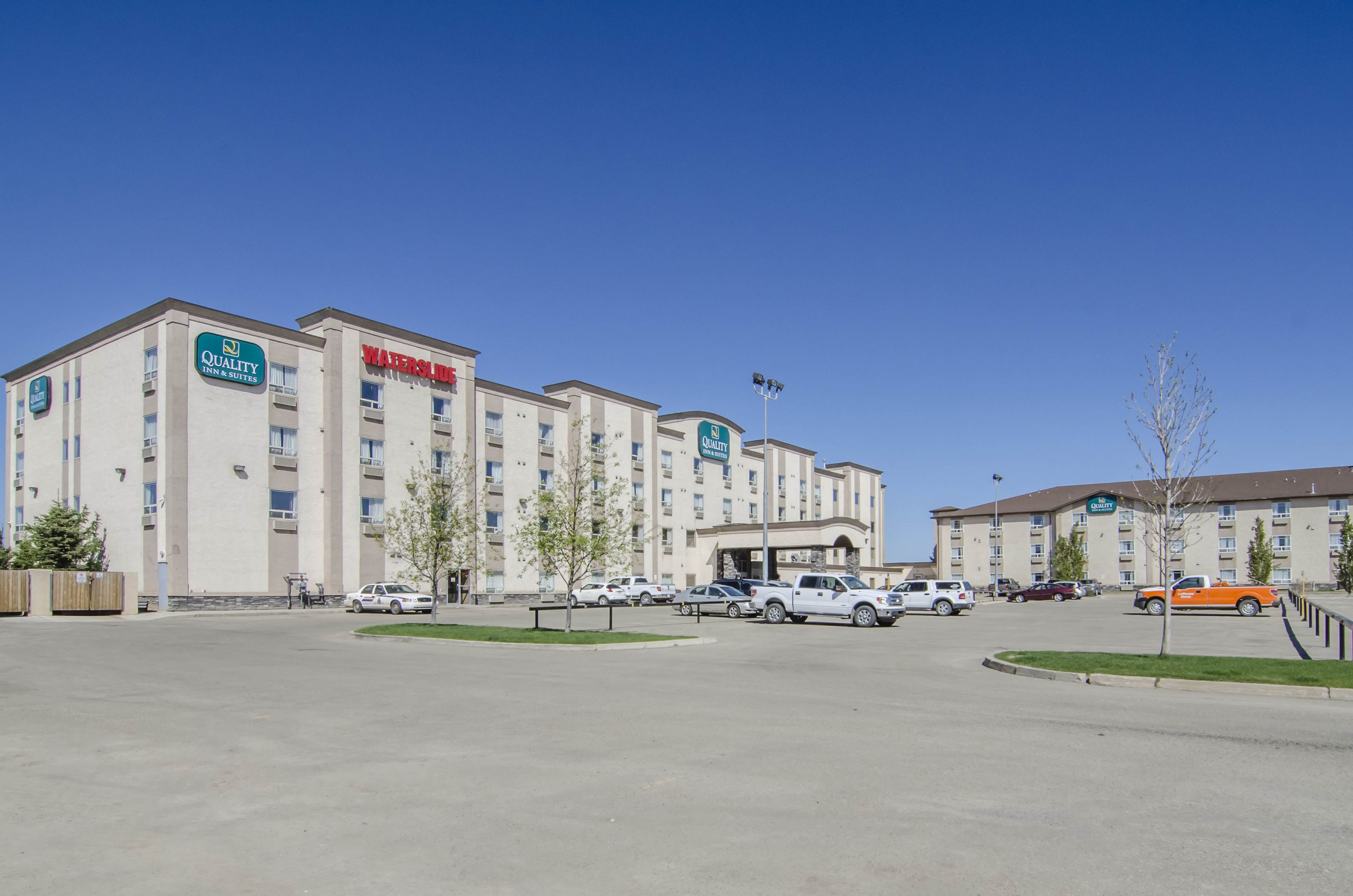 A hotel with multiple buildings, a parking lot, and several cars.