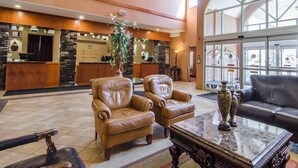 A lobby with a reception desk, leather seating, a large vase, and a marble coffee table. - Quality Inn & Suites (Grande Prairie)