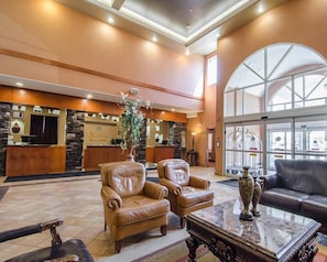 A lobby with a reception desk, leather seating, a large vase, and a marble coffee table.