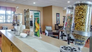 A self-service breakfast area with various food dispensers, a 'Healthy' sign, and a counter with a coffee machine. - Quality Inn & Suites (Grande Prairie)