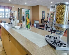 A self-service breakfast area with various food dispensers, a 'Healthy' sign, and a counter with a coffee machine.