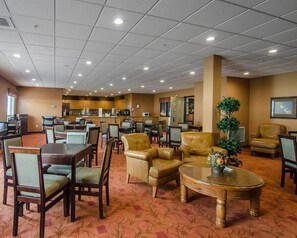 A hotel lobby with multiple seating areas, a bar, and a reception desk. - Quality Inn & Suites (Grande Prairie)