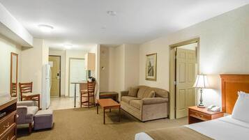 Una habitación de hotel con una cama, un sofá, un escritorio, una silla, una lámpara y un aparador.