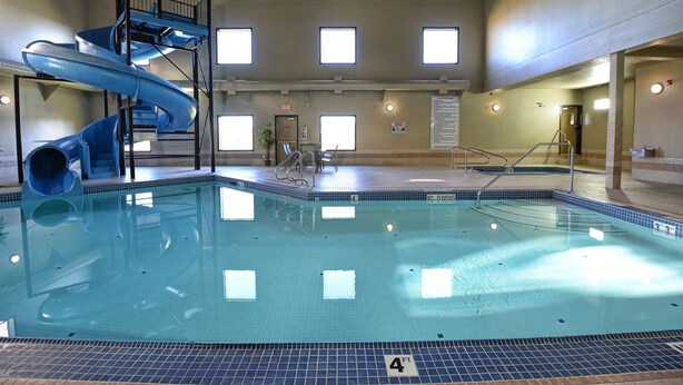 An indoor swimming pool with a blue slide and a 4 FT depth marker. - Quality Inn & Suites (Grande Prairie)