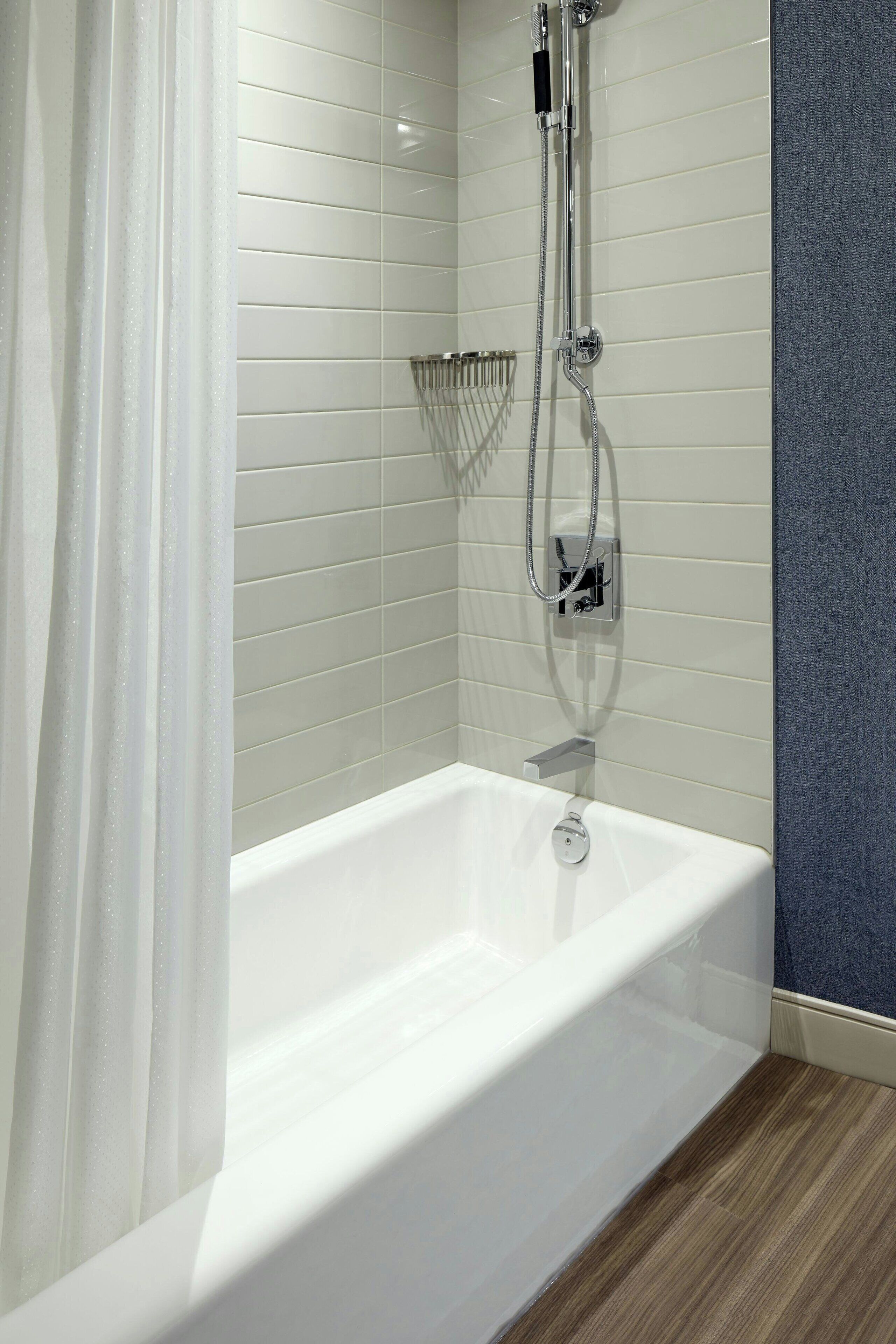 Un baño moderno con una bañera blanca, un cabezal de ducha y un perchero.