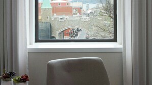 Una habitación con un ventanal grande, una silla y dos plantas en macetas sobre una mesita.