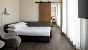 Una habitación de hotel moderna con una cama, una silla, un escritorio y un televisor.