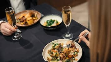 A dining table with three plates of food and two glasses of wine.