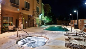 A pool area with hot tubs, lounge chairs, and a building with multiple windows and a stone pillar. - Fairfield by Marriott Inn & Suites Roswell (Roswell)