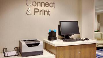 A desk with a printer, a computer, and a keyboard.
