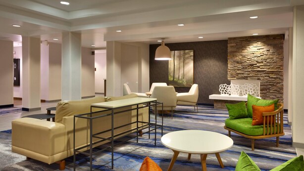 A modern hotel lobby with a seating area featuring a sofa, chairs, and a small table. - Fairfield by Marriott Inn & Suites Roswell (Roswell)