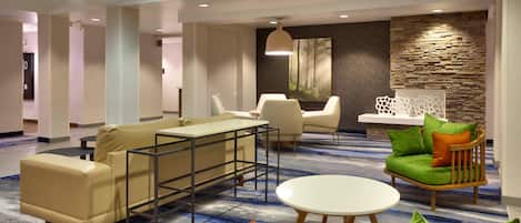 Un moderno vestíbulo de hotel con un área de estar que incluye un sofá, sillas y una mesita.