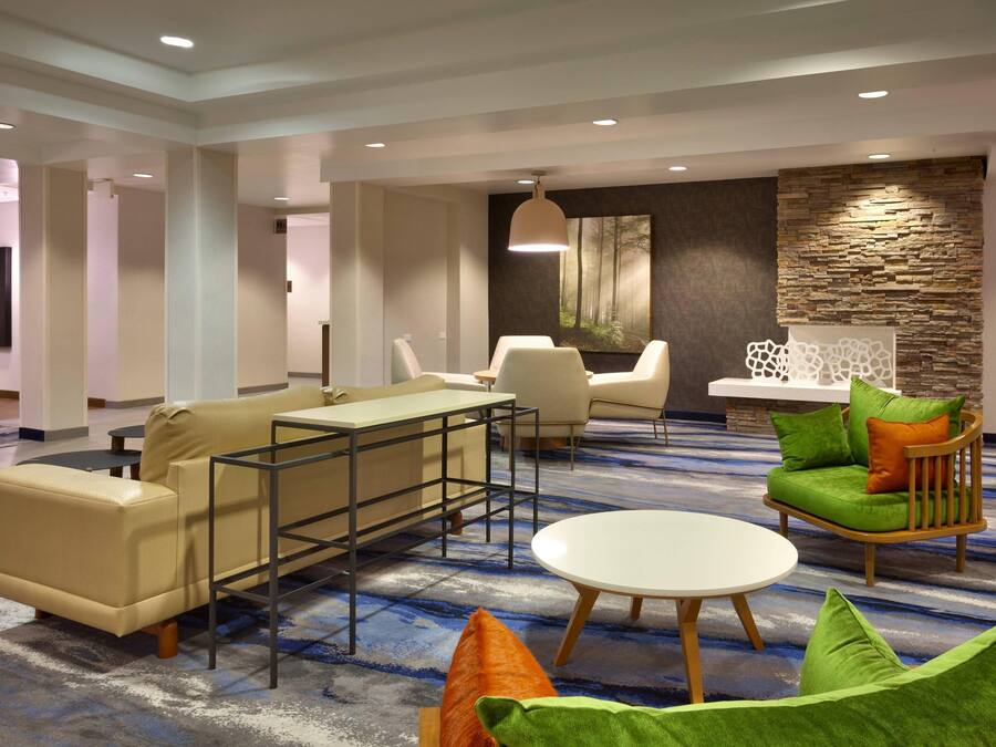 Un moderno vestíbulo de hotel con un área de estar que incluye un sofá, sillas y una mesita.