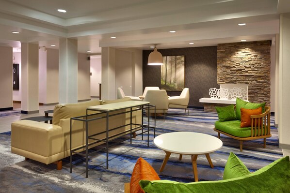 A modern hotel lobby with a seating area featuring a sofa, chairs, and a small table. - Fairfield by Marriott Inn & Suites Roswell (Roswell)