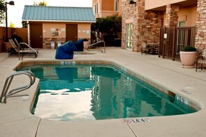 A swimming pool with a blue cover, a lounge chair, and a stone building with a metal gate in the background. - Fairfield by Marriott Inn & Suites Roswell (Roswell)