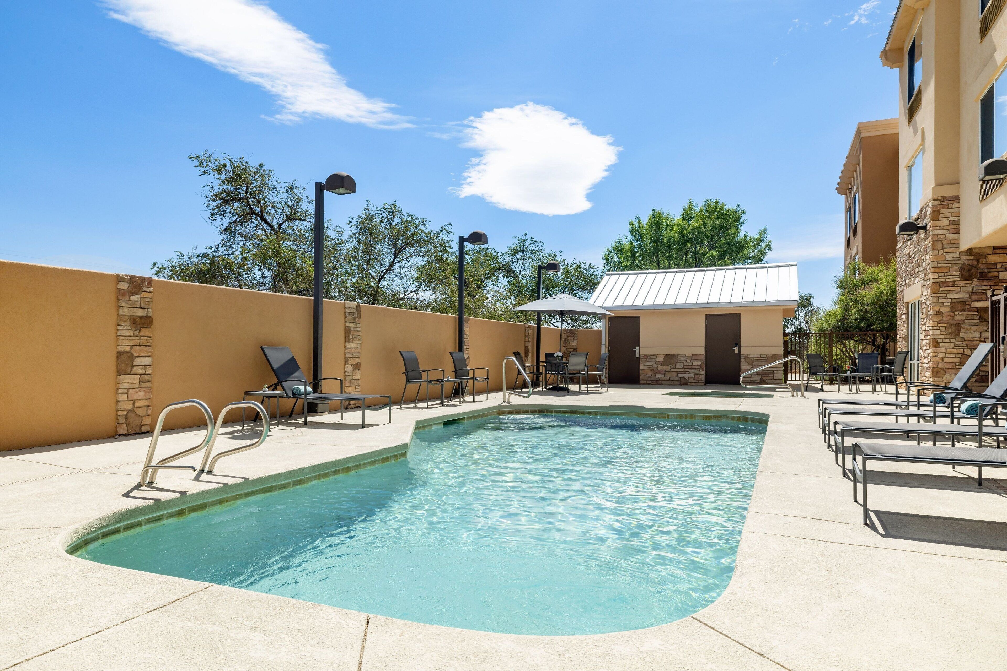 A swimming pool with lounge chairs and a small building in the background.