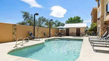 A swimming pool with lounge chairs and a small building in the background.