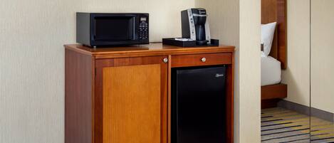 A compact minibar with a microwave, coffee maker, and refrigerator.