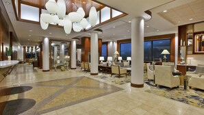 A spacious lobby with a high ceiling, large chandeliers, and a mix of seating areas including sofas and armchairs. - Hilton Garden Inn Portland Downtown Waterfront (Portland)