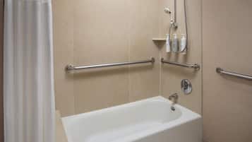 A bathroom with a bathtub, grab bars, and a showerhead.
